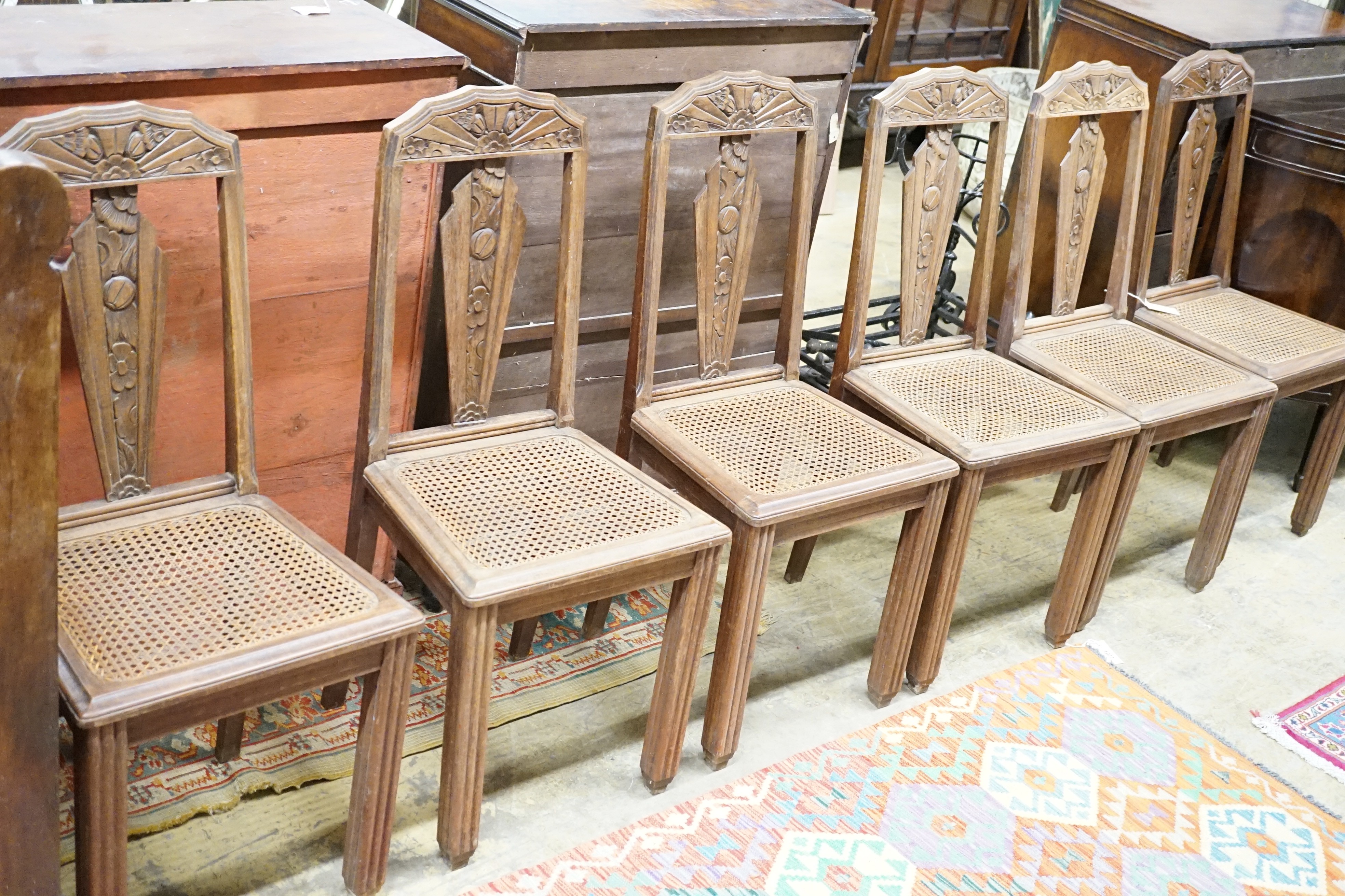 A set of six Continental Art Deco carved and stained beech salon chairs with caned seats, width 44cm, height 96cm